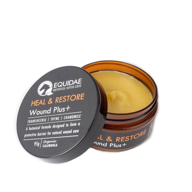 Tin of Heal and Restore wound ointment for horses being applied to horse with scratches on legs